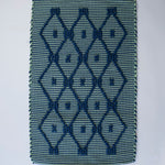 A madcap cottage navy blue and green striped accent rug with a lattice motif across the front