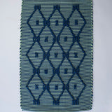 A madcap cottage navy blue and green striped accent rug with a lattice motif across the front