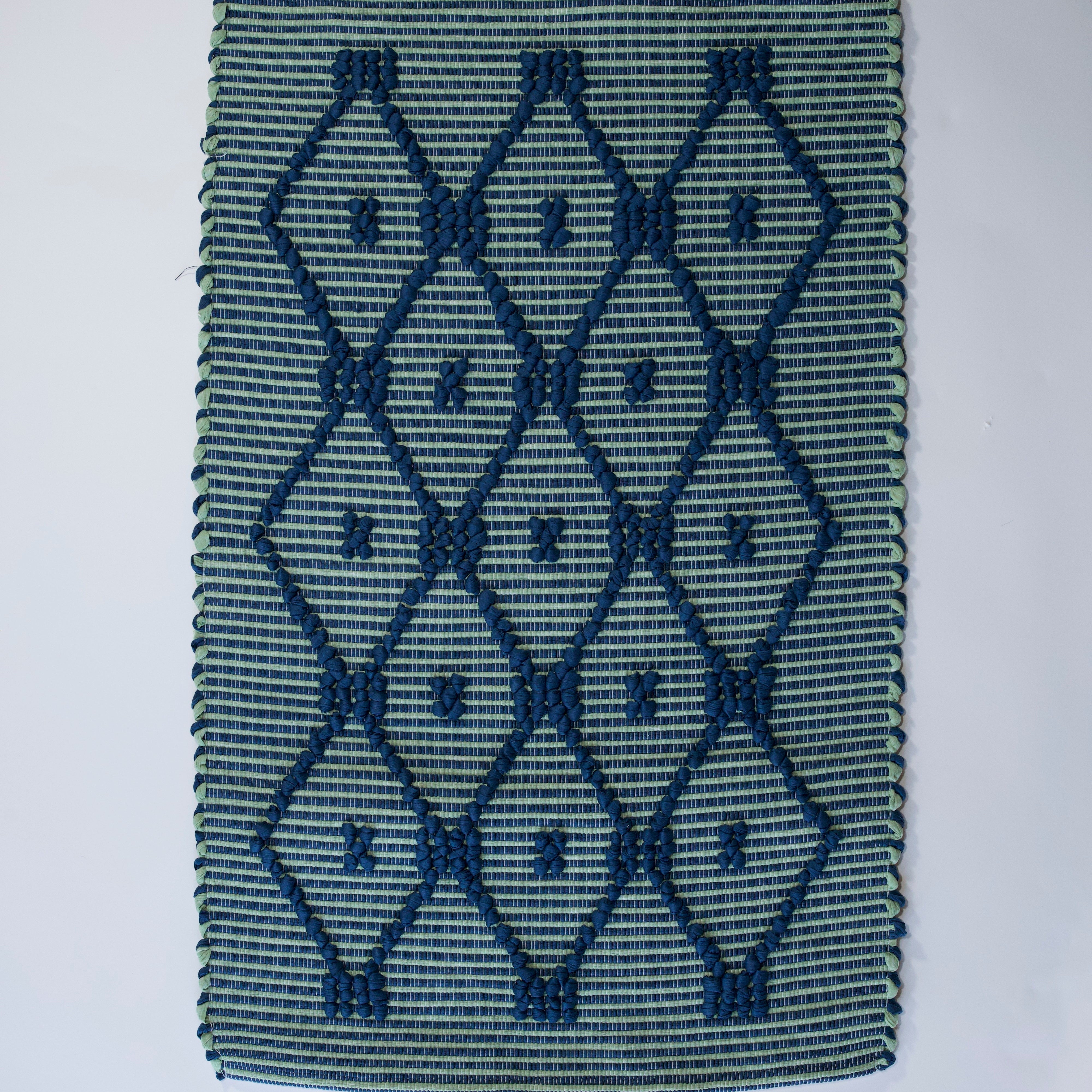 A madcap cottage navy blue and green striped accent rug with a lattice motif across the front