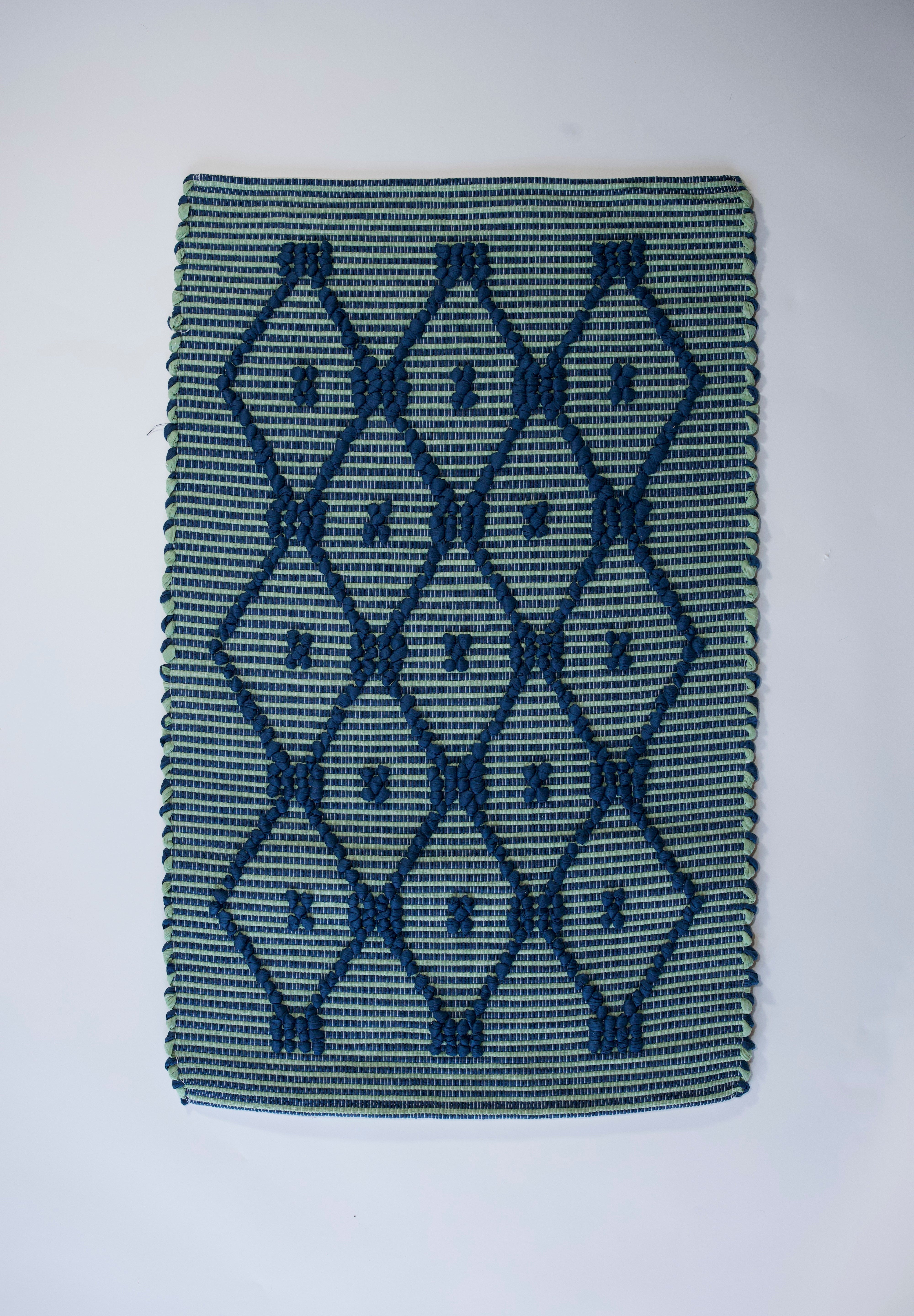 A madcap cottage navy blue and green striped accent rug with a lattice motif across the front