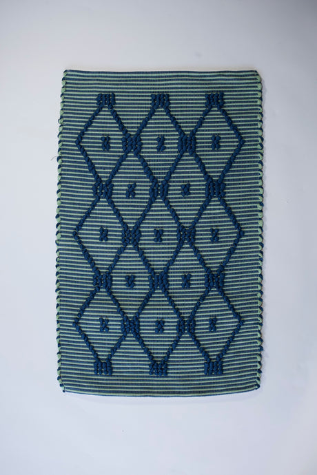 A madcap cottage navy blue and green striped accent rug with a lattice motif across the front