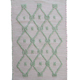 A madcap cottage pink and green striped accent rug with a lattice motif across the front