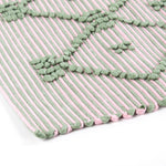 close up look of A pink/green accent rug with a lattice pattern on it