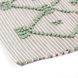 close up look of A pink/green accent rug with a lattice pattern on it