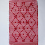 A madcap cottage white and red striped accent rug with a lattice motif across the front.