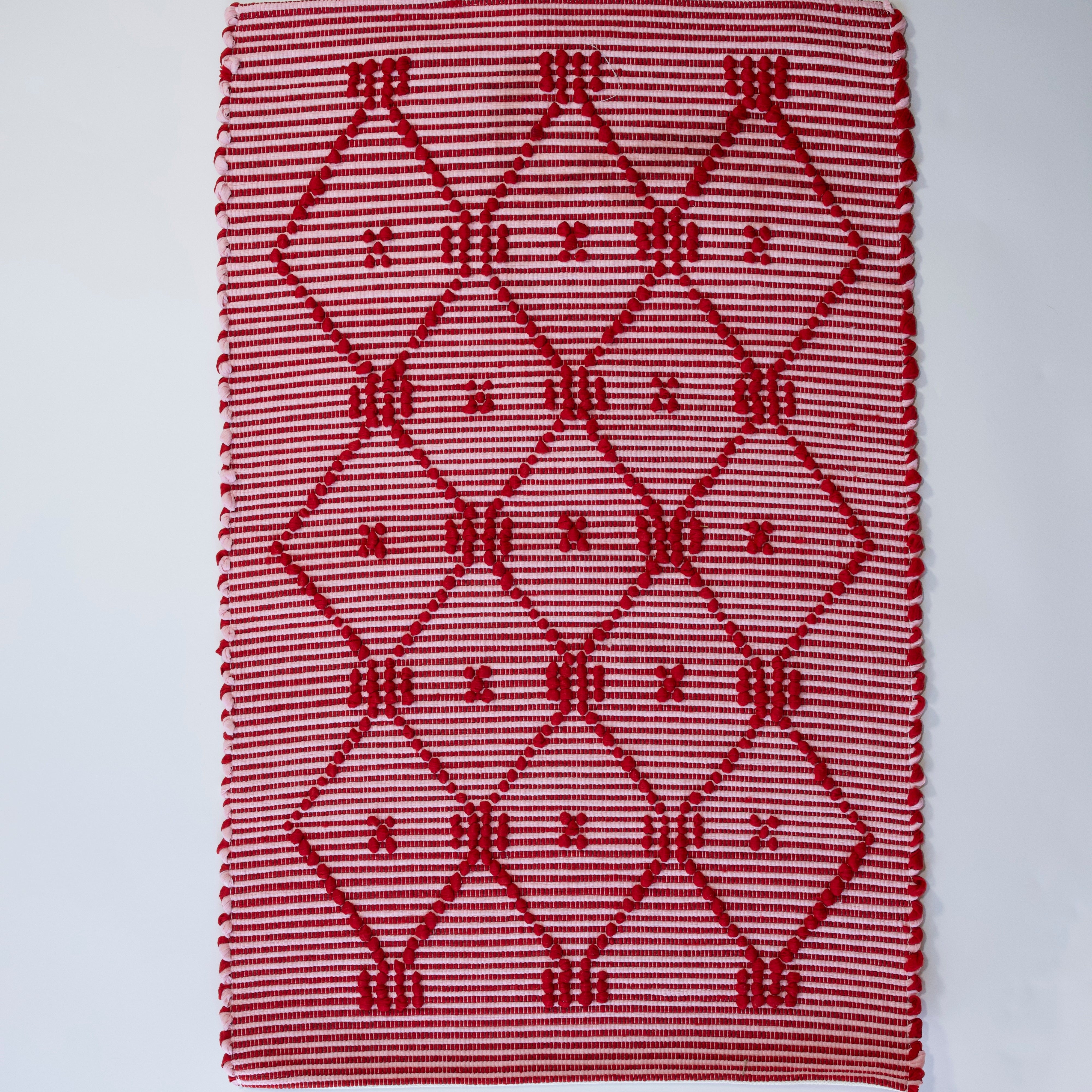 A madcap cottage white and red striped accent rug with a lattice motif across the front.