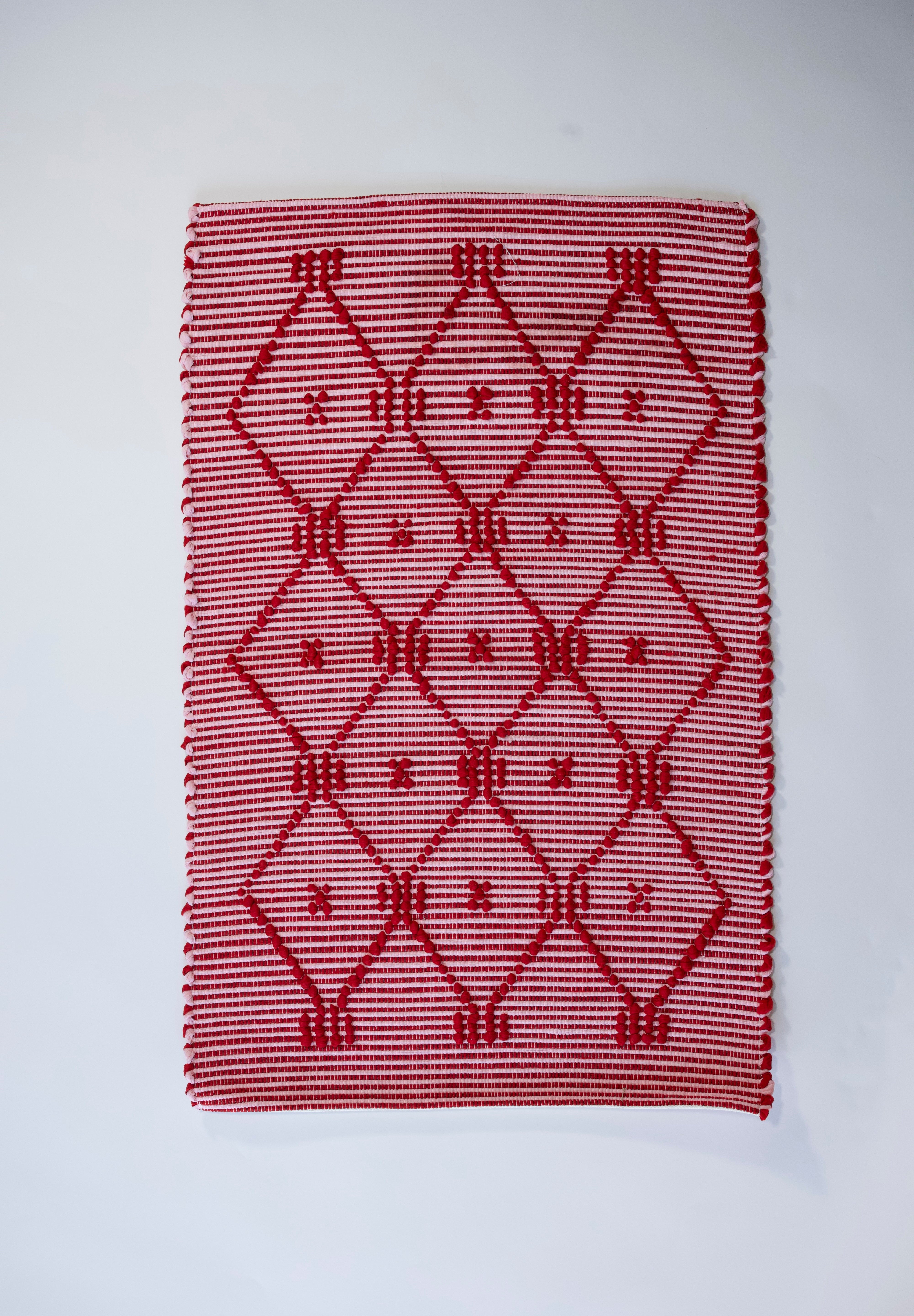 A madcap cottage white and red striped accent rug with a lattice motif across the front.
