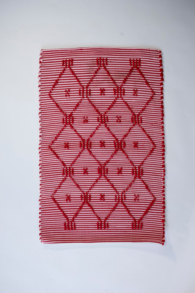 A madcap cottage white and red striped accent rug with a lattice motif across the front.
