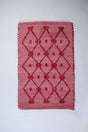 A madcap cottage white and red striped accent rug with a lattice motif across the front.