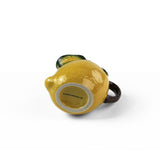 Lemon pitcher yellow ceramic bottom view with textured lemon shape, green leaf accents, and dark curved handle.