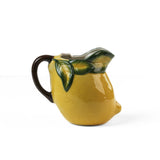 Lemon pitcher yellow ceramic main view with green leaf details and curved dark handle on a white background