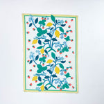 Christmas tea towel featuring a bright botanical design with yellow lemons, red strawberries, and green leaves on a white background bordered with soft yellow and green trim.