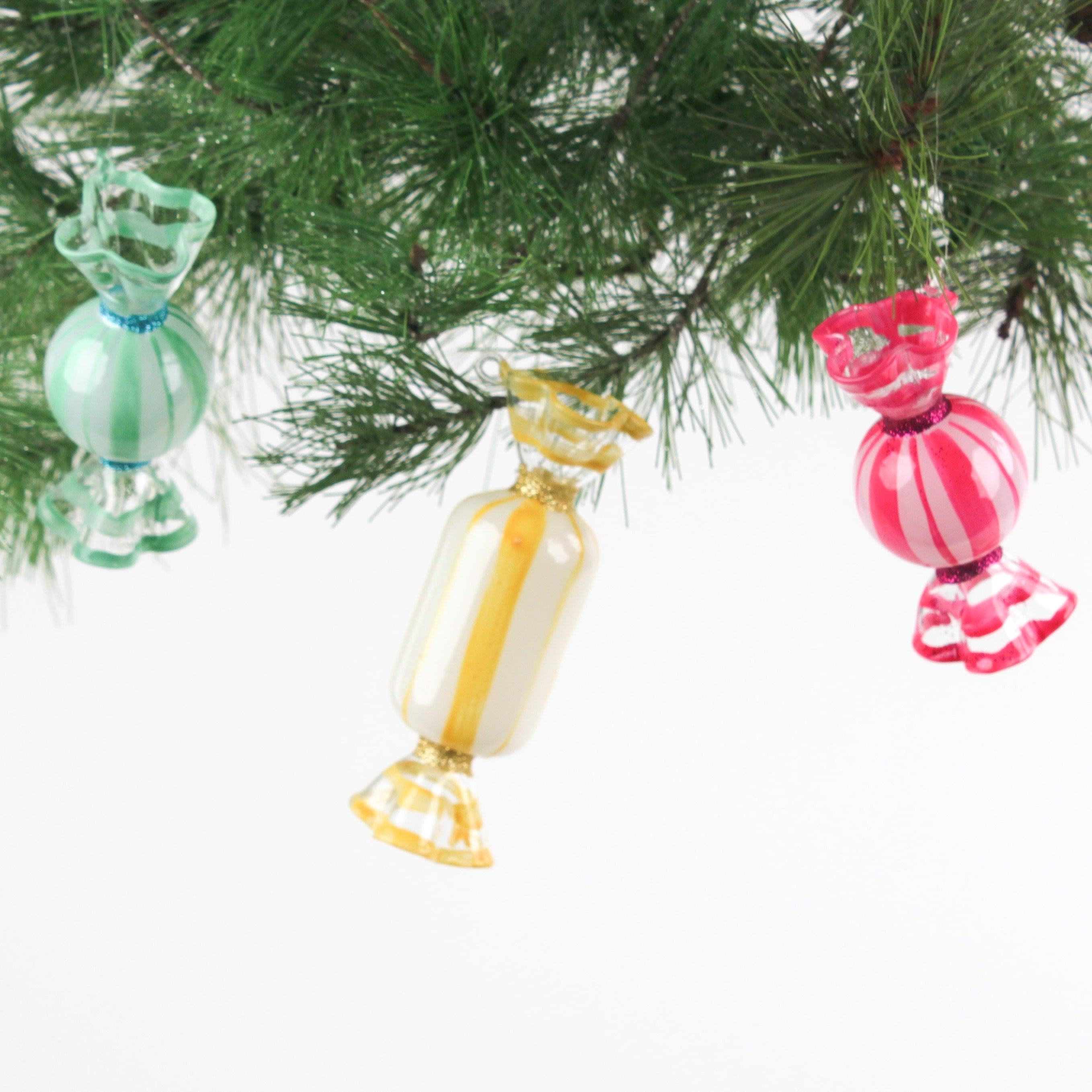 Colorful glass candy ornaments hanging on a Christmas tree.