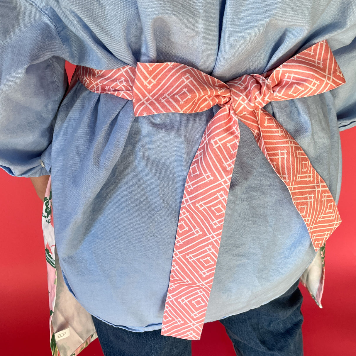 Person wearing a blue shirt with a red patterned bow on a red background