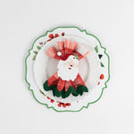 Lifestyle shot of the cottage grove geranium red floral plate with a white plate resting on it, holding a napkin with a santa napkin ring.