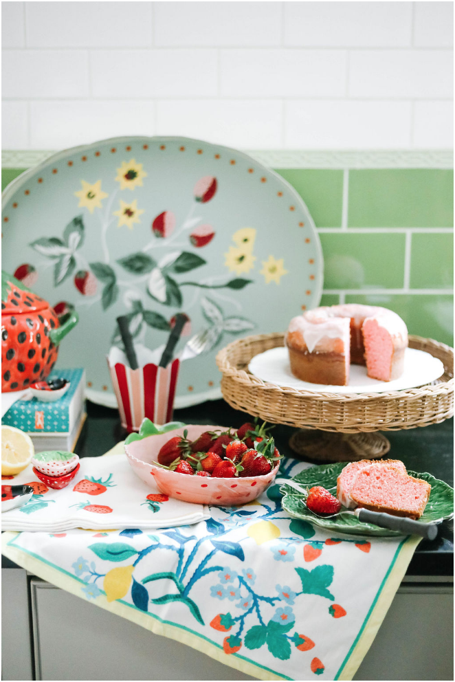 a strawberry decor kitchen scene featuring strawberry motif trays, bowls, tea towels. 