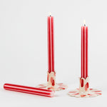lit 3 gold red and white striped taper candles lying in a white background
