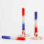 lit trio of colorful taper candles in a mix of white, blue and orange. 
