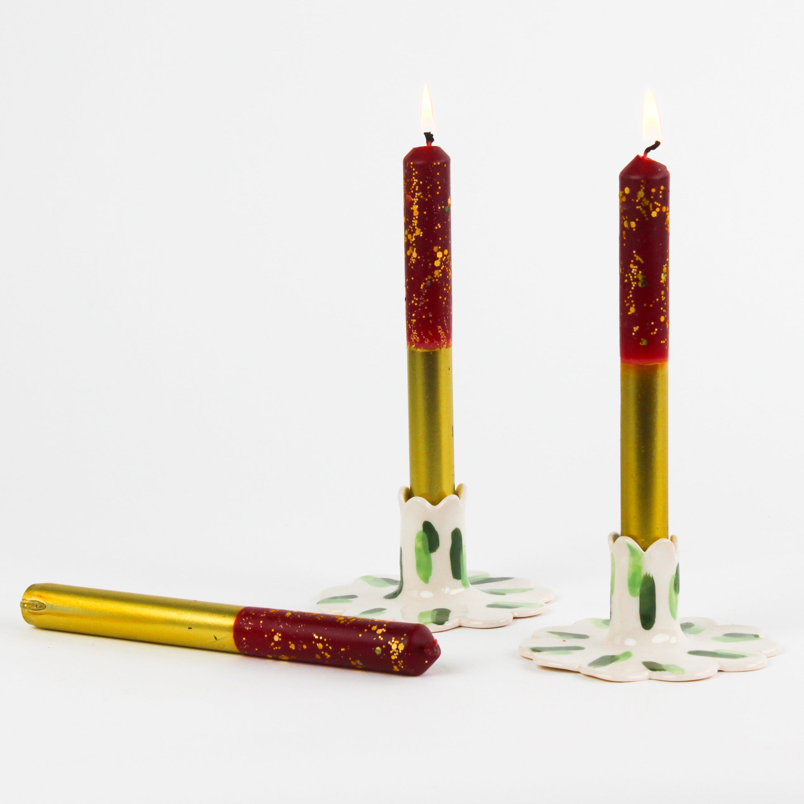 lit 3 plum pudding gold taper candles lying in a white background
