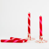 lit 4 Red Pink Taper Candles laying on a white background