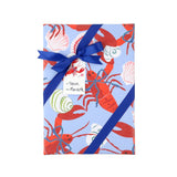 Coastal gift wrap featuring vibrant red lobsters, decorative seashells, and playful patterns on blue paper.