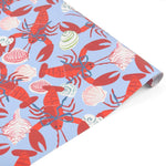 Coastal gift wrap featuring vibrant red lobsters, decorative seashells, and playful patterns on blue paper.