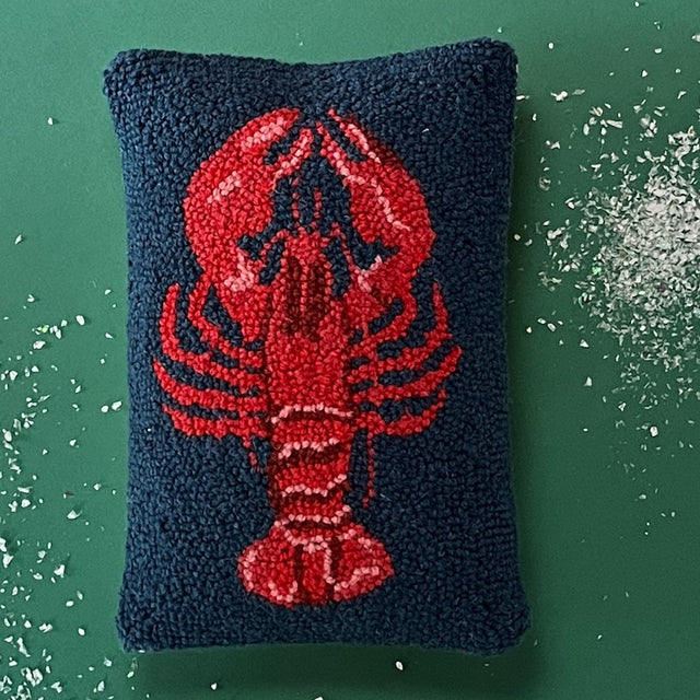 a navy blue hooked wool pillow with a central large red lobster motif