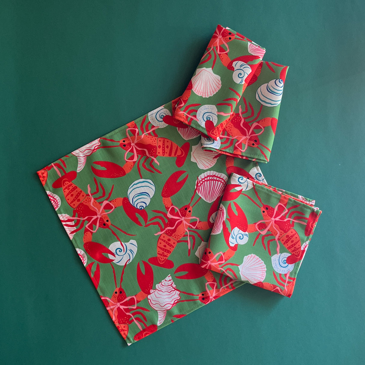A set of four cloth dinner napkins made with a lobster and shell motif patterned fabric