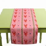 a pink table runner with stripes of lobsters, ribbon, and green squiggles.