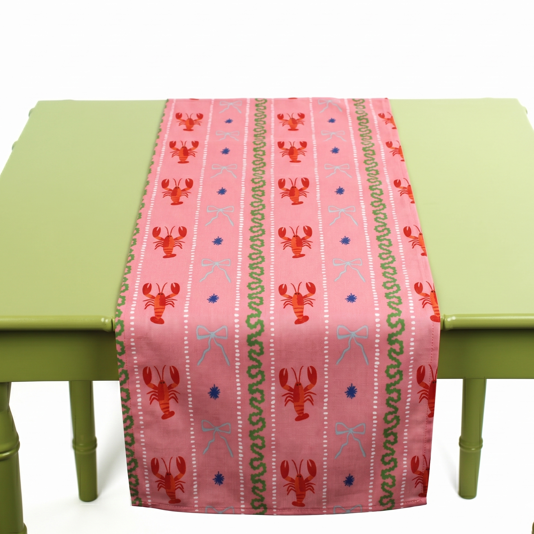 a pink table runner with stripes of lobsters, ribbon, and green squiggles.