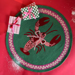 A round green and pink rug with a central red and pink lobster motif.