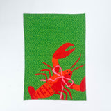 Green Christmas tea towel with a festive red lobster illustration tied with a pink bow