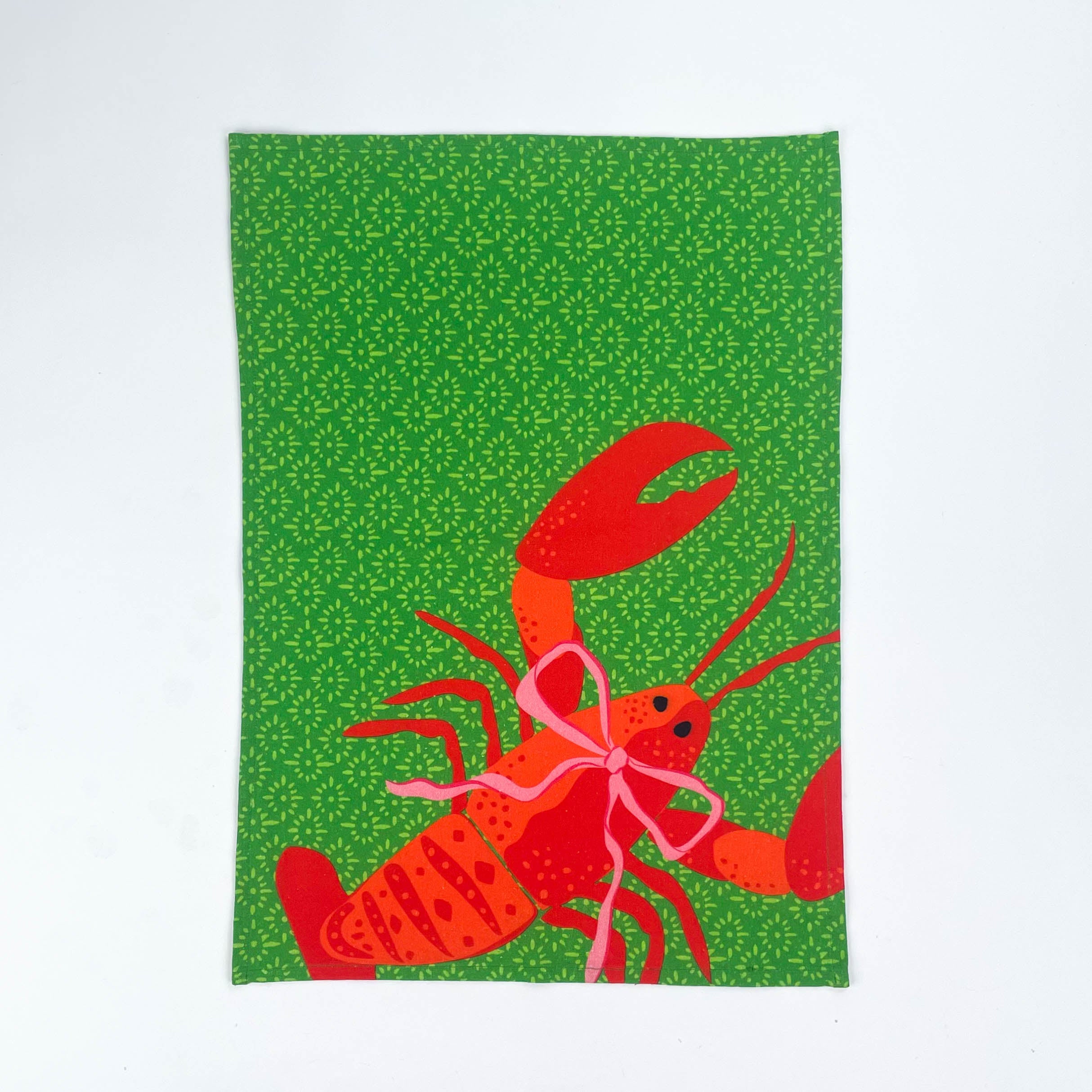 Green Christmas tea towel with a festive red lobster illustration tied with a pink bow