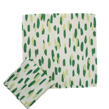 A green and white napkin featuring brushstroke motifs in different shades of green. 