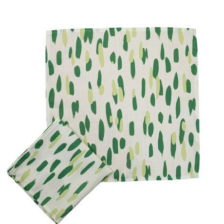 A green and white napkin featuring brushstroke motifs in different shades of green. 