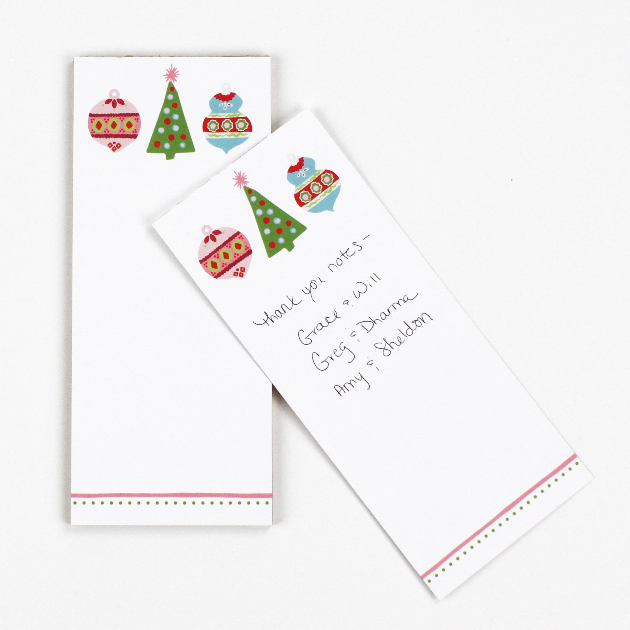 a skinny luxury christmas notepads with ornament and holly motifs against a white background.
