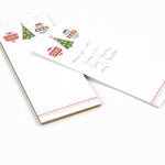 a skinny luxury christmas notepads with ornament and holly motifs against a white background.