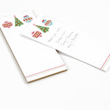 a skinny luxury christmas notepads with ornament and holly motifs against a white background.
