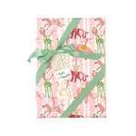 Whimsical Christmas gift wrap featuring festive giraffes, monkeys, zebras, and swans against playful pink stripes.