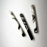 Three marbled black-and-white taper candles are lying horizontally.