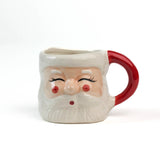 Ceramic Christmas santa mug with a jolly santa face design with red cheeks and a red handle on a white background