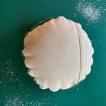 Back view of a round decorative pillow with a soft beige fabric and envelope-style closure.