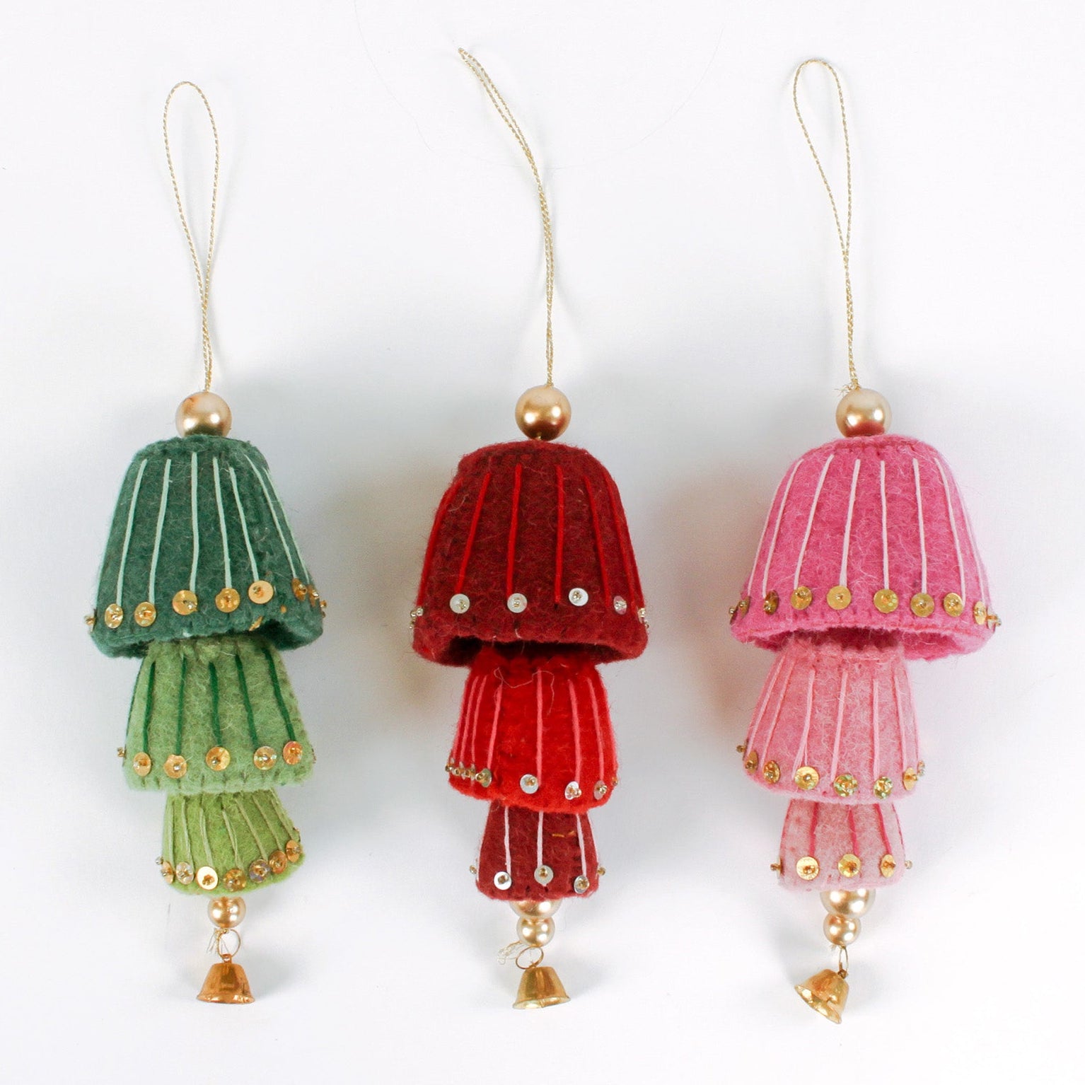 Three decorative felt christmas ornaments in green, red, and pink and gold sequin details on a white background