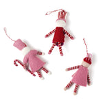 reverse side of three madcap cottage Christmas felt nutcracker ornaments in red and white striped outfit on a white background