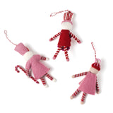 reverse side of three madcap cottage Christmas felt nutcracker ornaments in red and white striped outfit on a white background