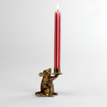 A gold mouse candle holder with a red striped candle in it against a white background