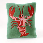Green pillow with a red lobster design on a white background