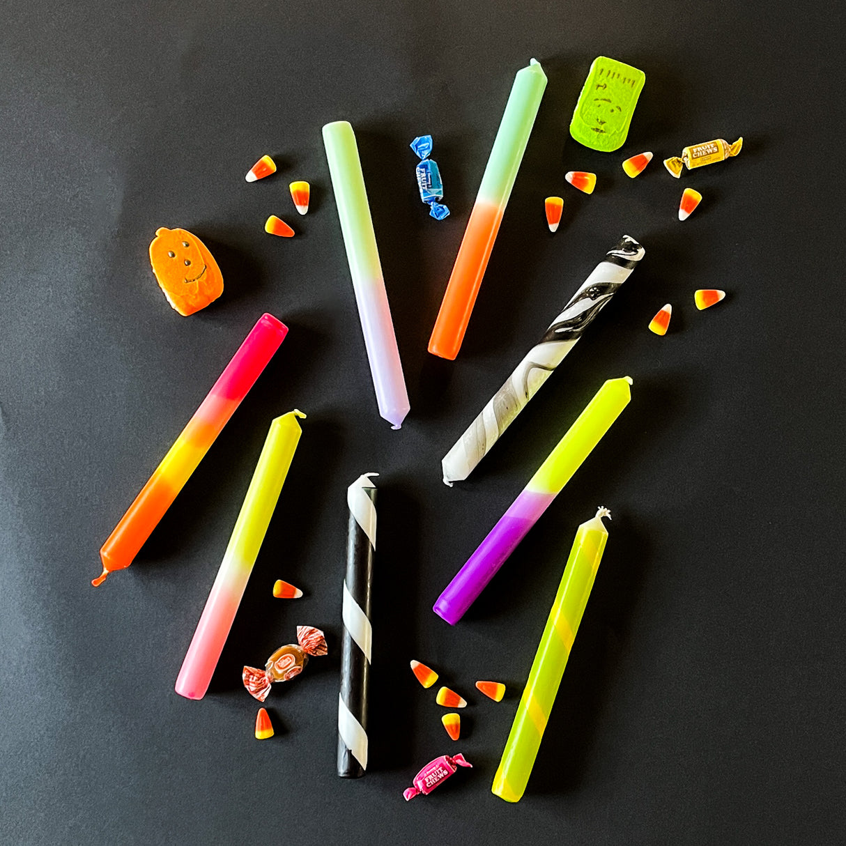 collection of taper candles on a black background, lying horizontally.