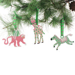 Set of colorful animal-themed Christmas ornaments hanging on a pine branch from Madcap Cottage. 