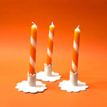 Three orange and white stripe halloween taper candles, on a white background.